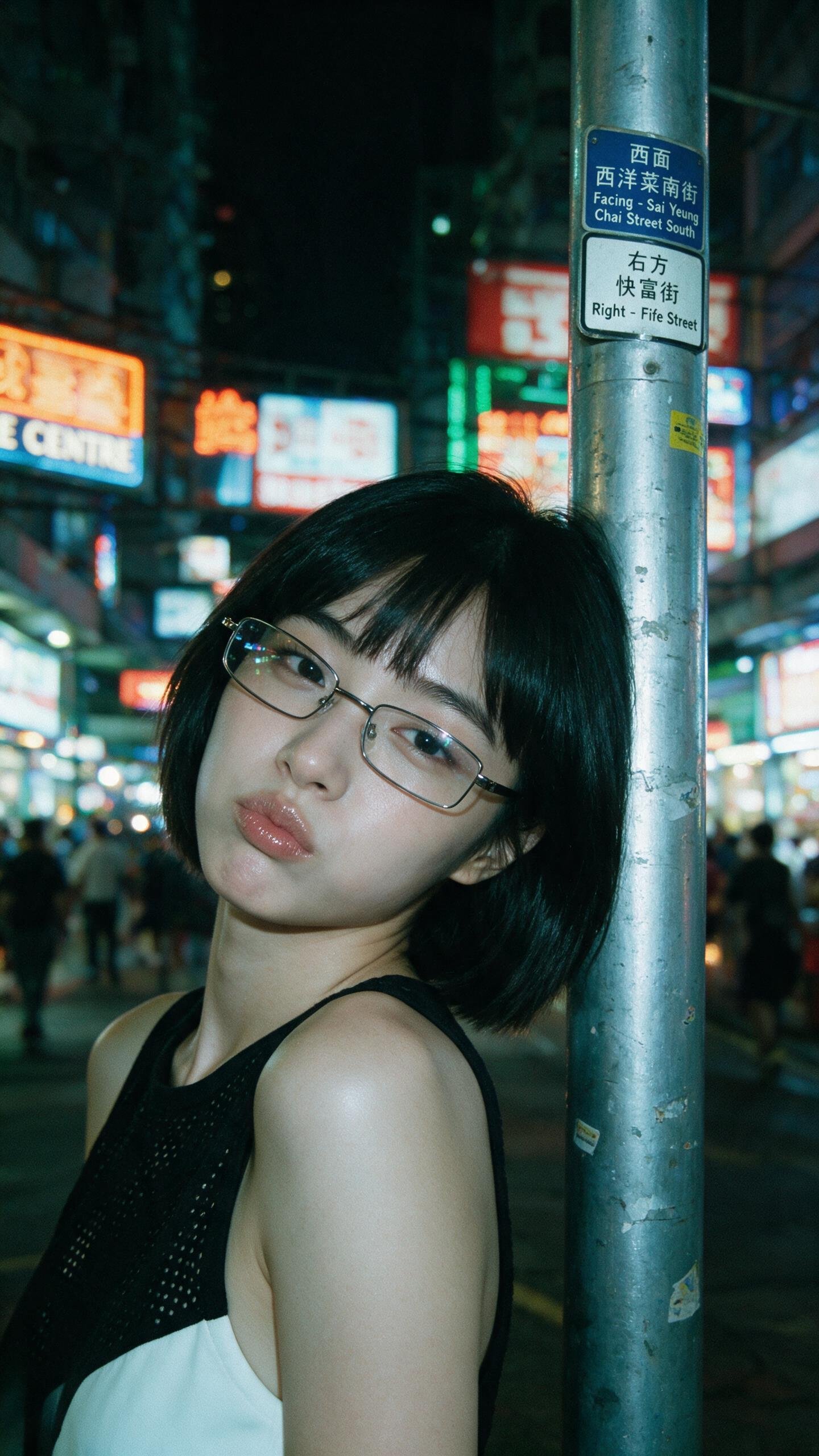 电影感特写夜景人像,一位年轻东亚女性,黑色波波头短发,齐刘海,佩戴细长方形金属框眼镜。她将左肩和侧脸靠在磨损的银色金属街柱上,头微微偏向镜头,表情柔和嘟嘴,直视镜头。她肤色白皙,眉形清晰,妆容自然,唇 — AI image prompt — Seedream 5